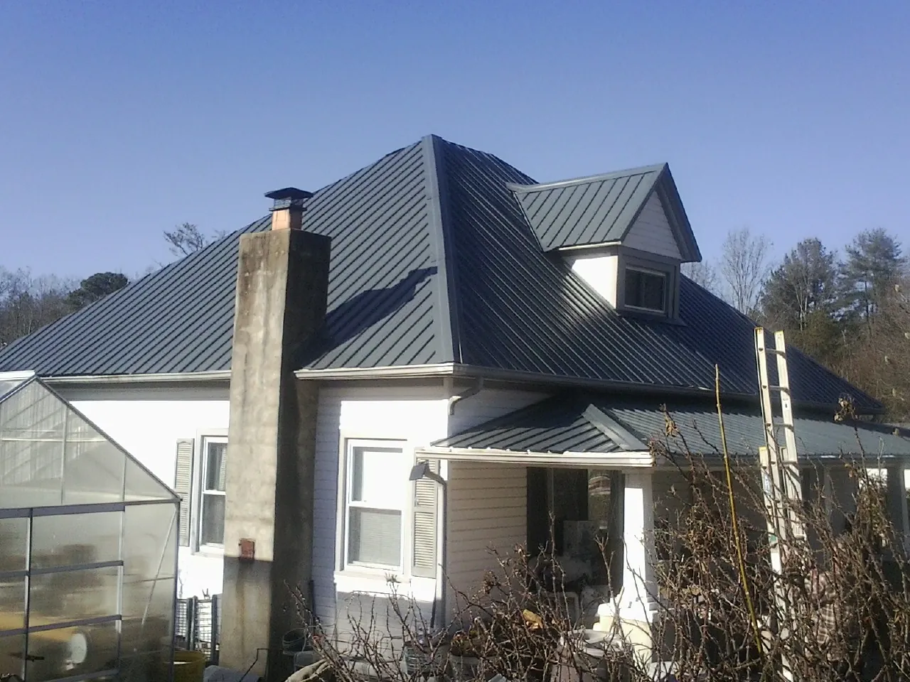 Dark blue standing seam metal roof on a white farmhouse with dormer — Slate & Tile Roof Repair by Roofing Brothers in Seven Springs