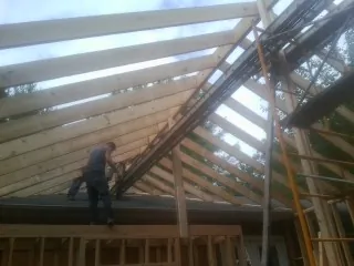 Rafters going up over a new addition with a worker on the wall in Seven Springs