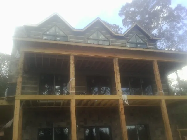 Dormers and porch framing on a large log home under construction — Roof Coating work by our crew in Seven Springs