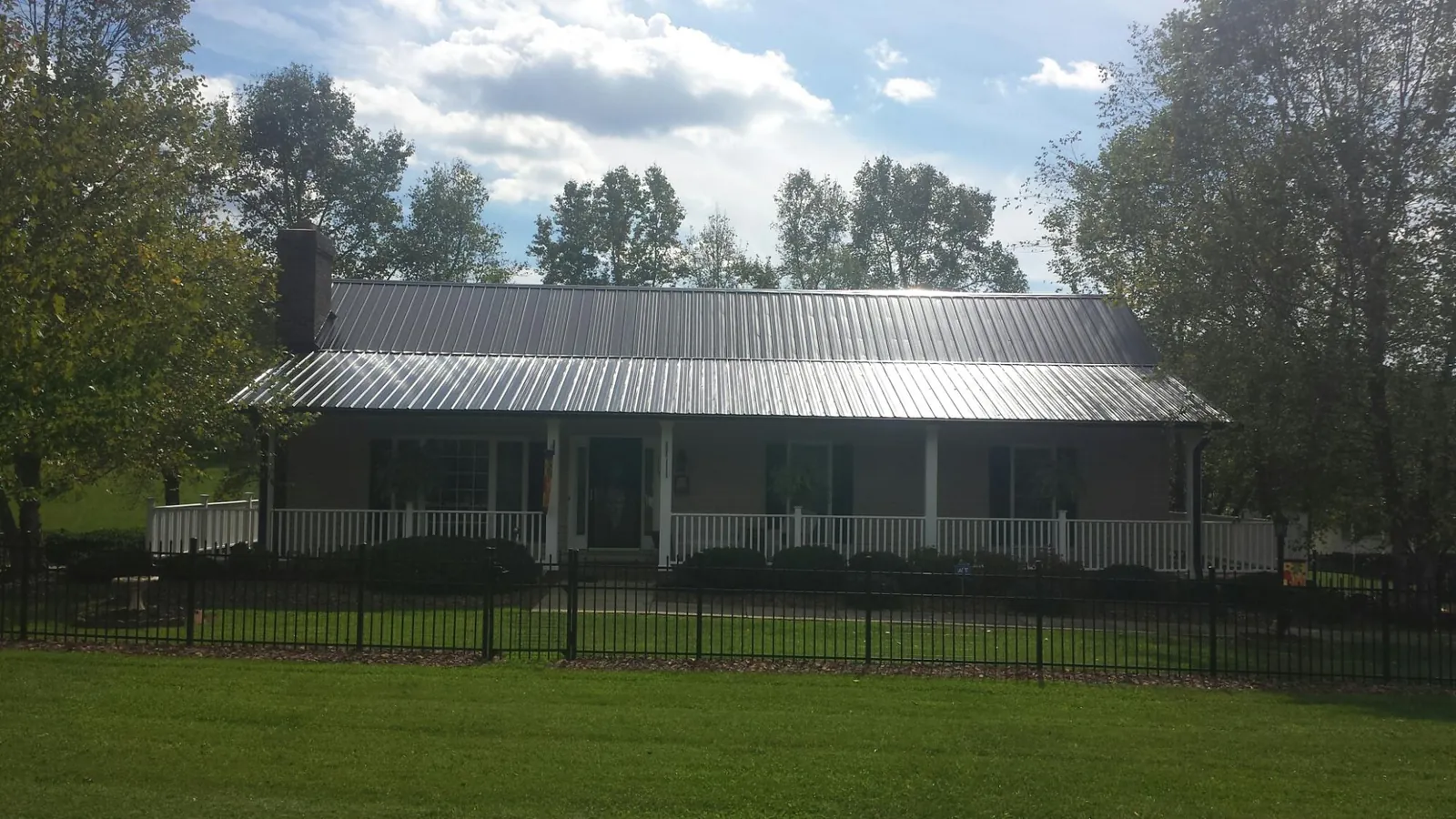 Gray metal roof on a brick ranch with a full width front porch — Gutter Guard Installation work by our crew in Seven Springs