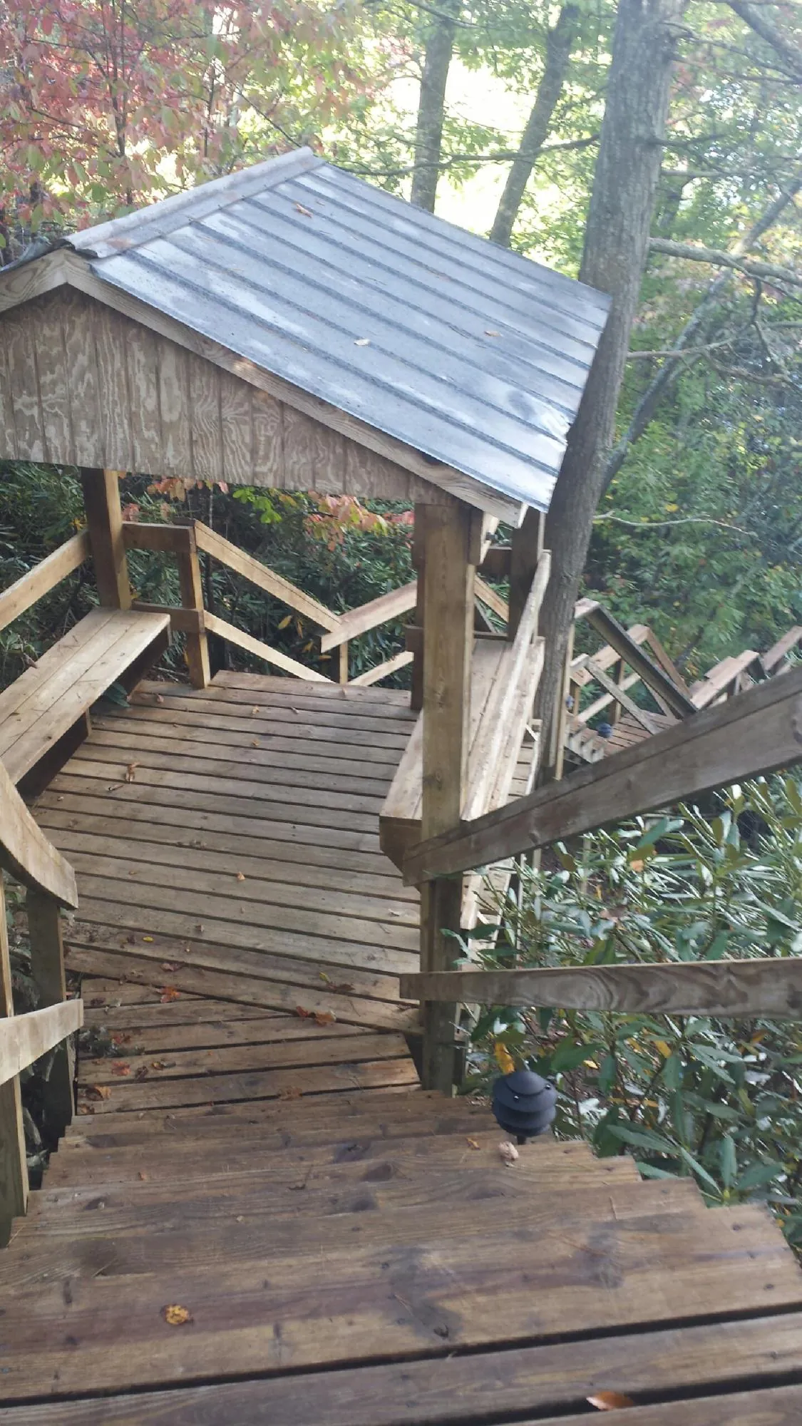 Metal roofed shelter over wooden steps on a wooded walkway — Skylight Repair & Installation work by our crew in Seven Springs