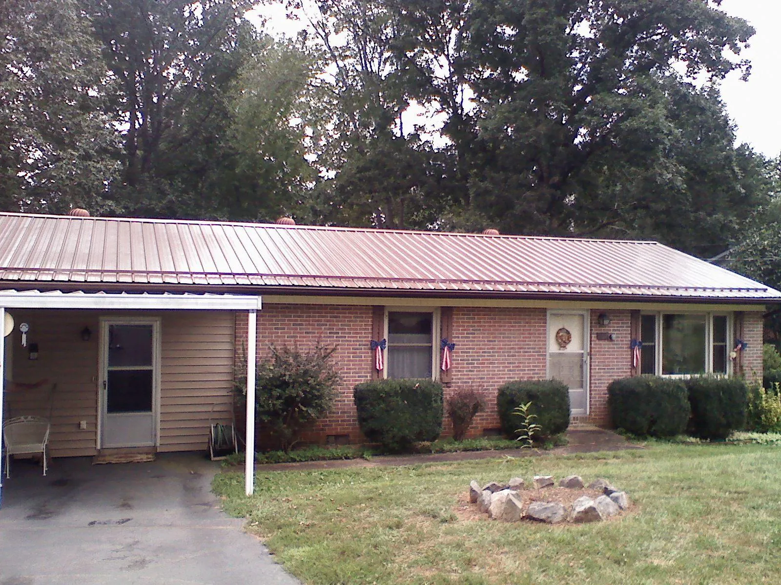 Bronze metal roof and carport on a brick ranch home — Roof Repair work by our crew in Seven Springs